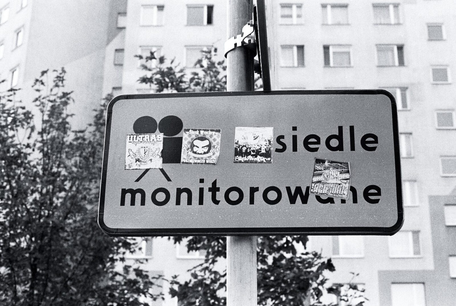 Szare zdjęcie znaku osiedle monitorowane zaklejonego nalepkami