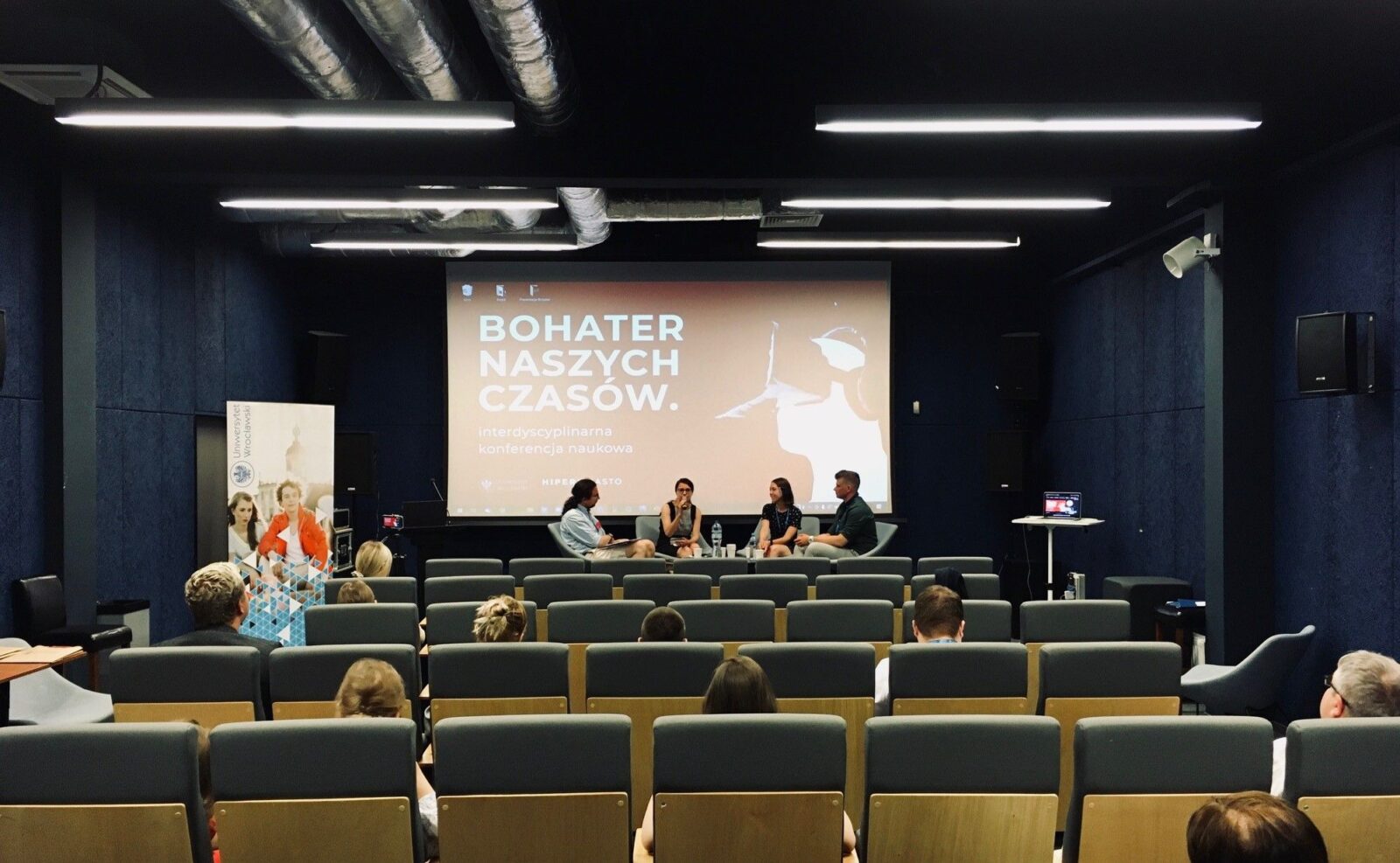 grupa osób na widowni i scenie sali konferencyjnej