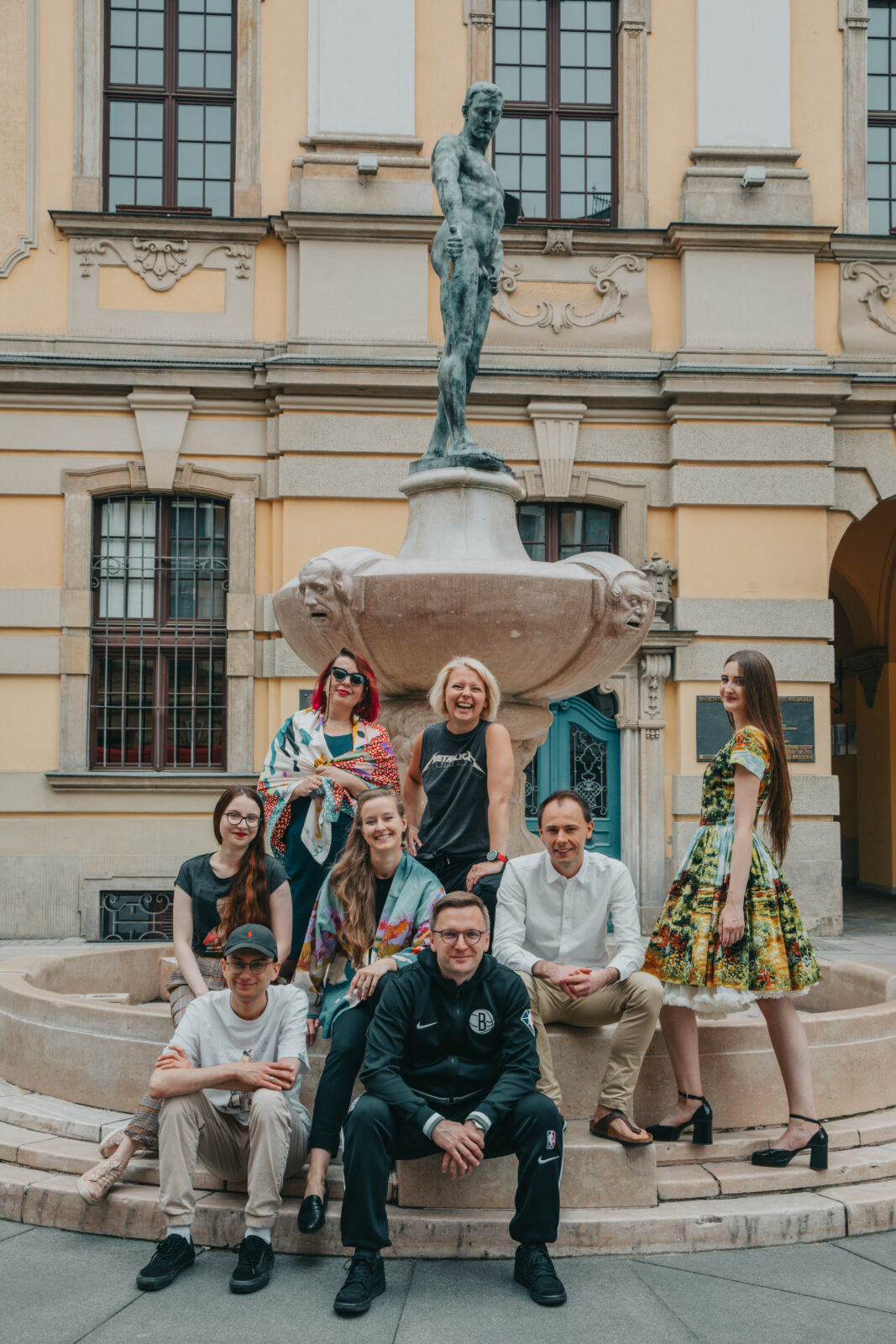 grupa osób przy zabytkowej fontannie z rzeźbą