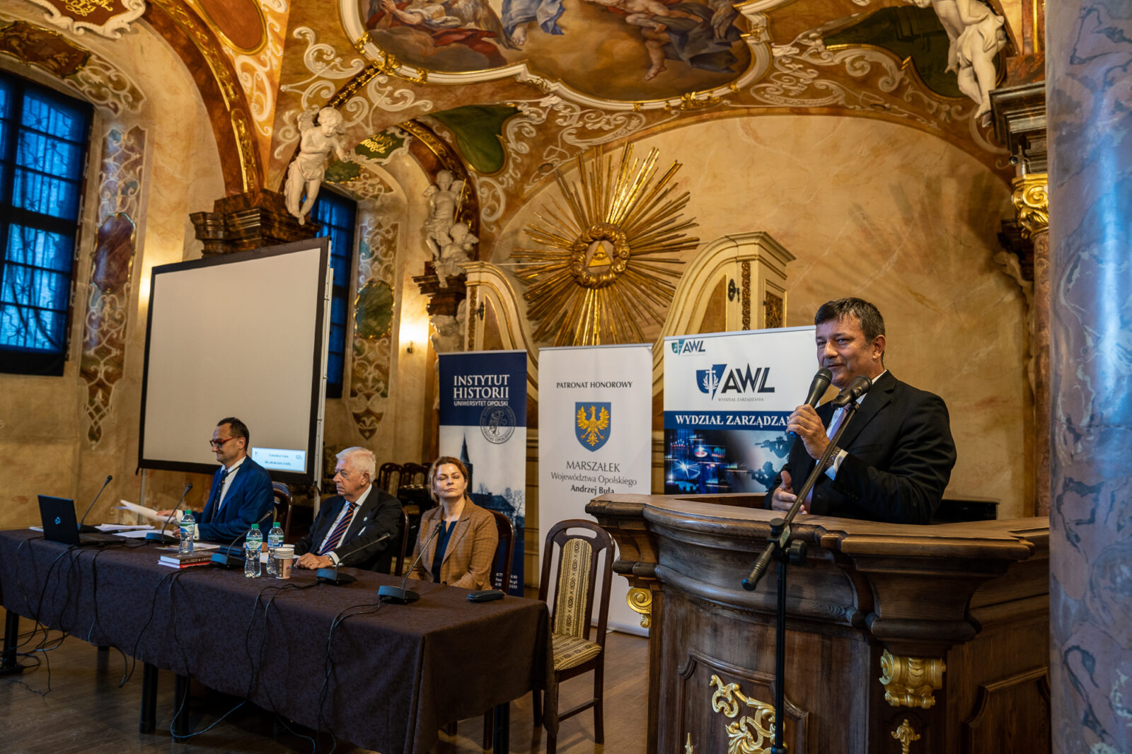Grupa osób na konferencji w zabytkowej sali