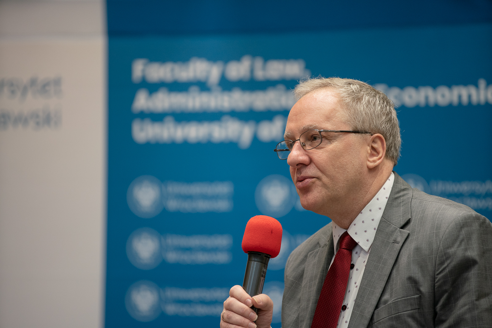 mężczyzna w średnim wieku przemawiający do mikrofonu