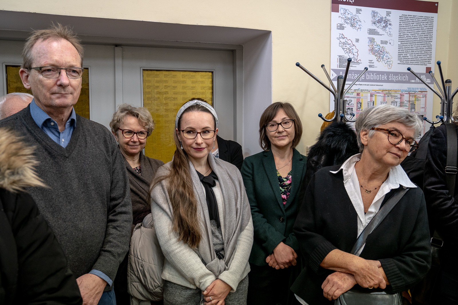 grupa osób w okularach z tyłu drzwi i wieszaki na ubranie