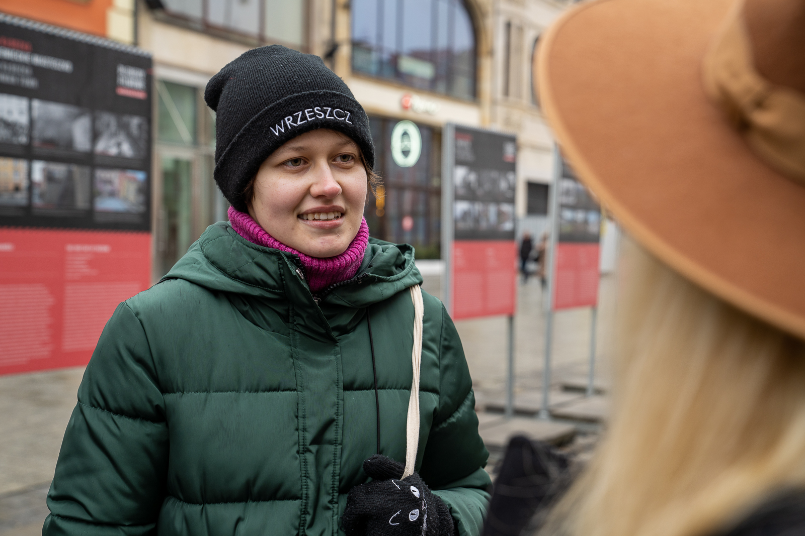 Młoda kobieta w zielonej kurtce i czarnej czapce