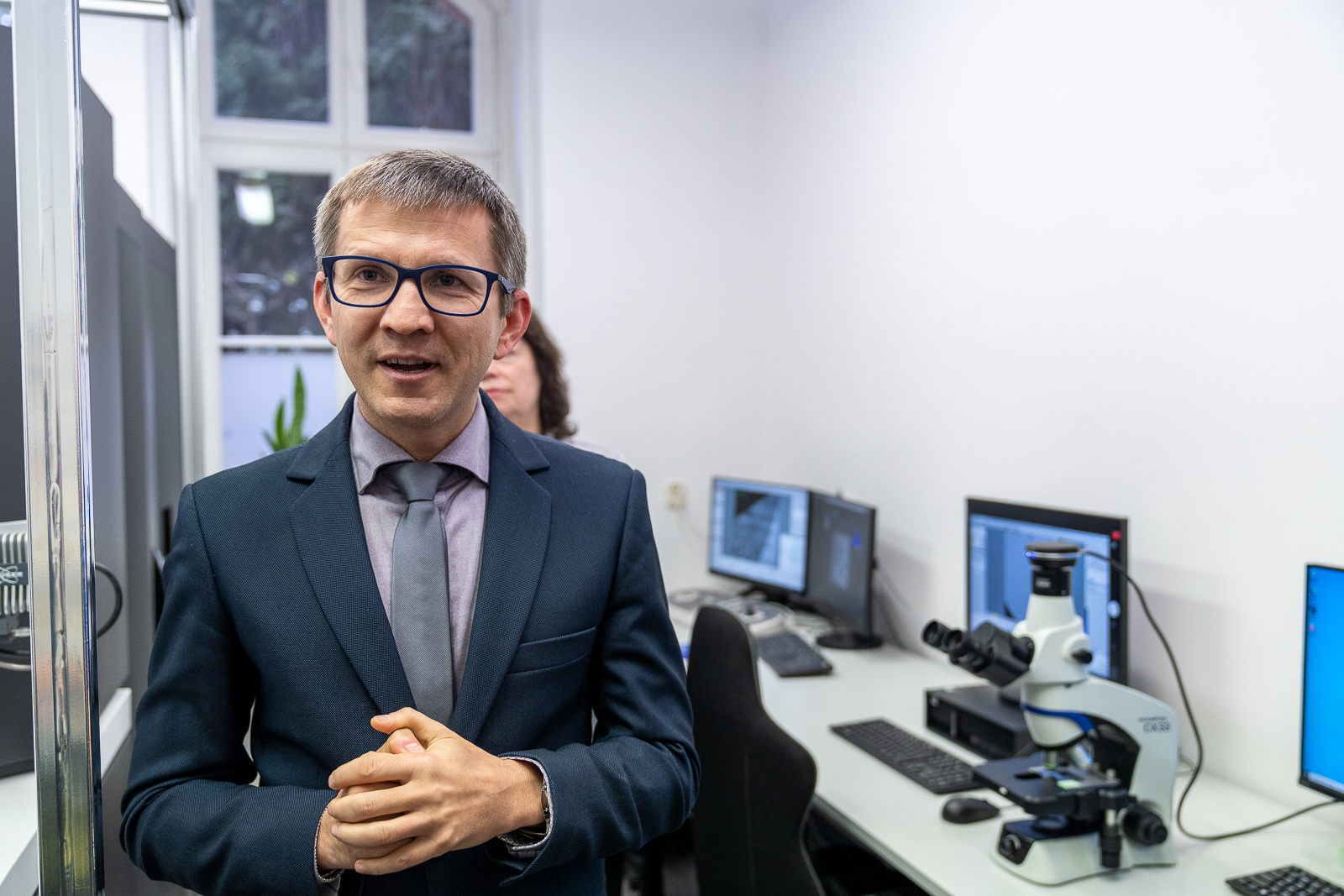 mężczyzna w garniturze stojacy obok biurek z komputerami