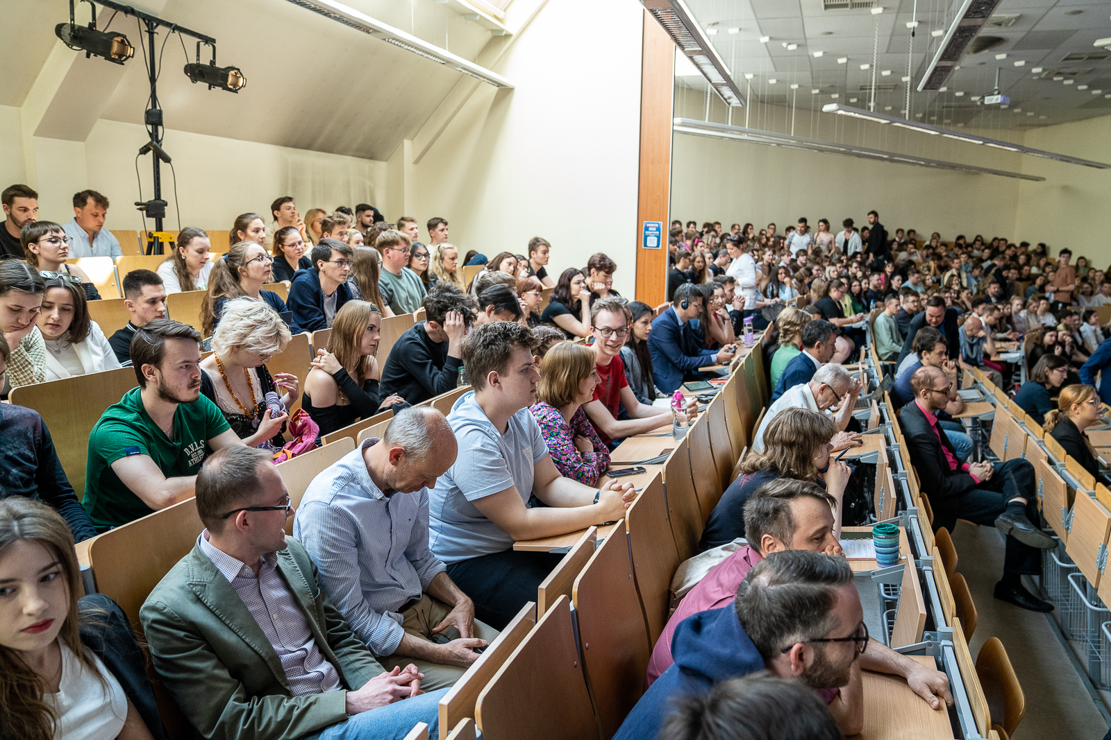 sala z wieloma osobami siedzącymi na krzesłach przy pulpitach