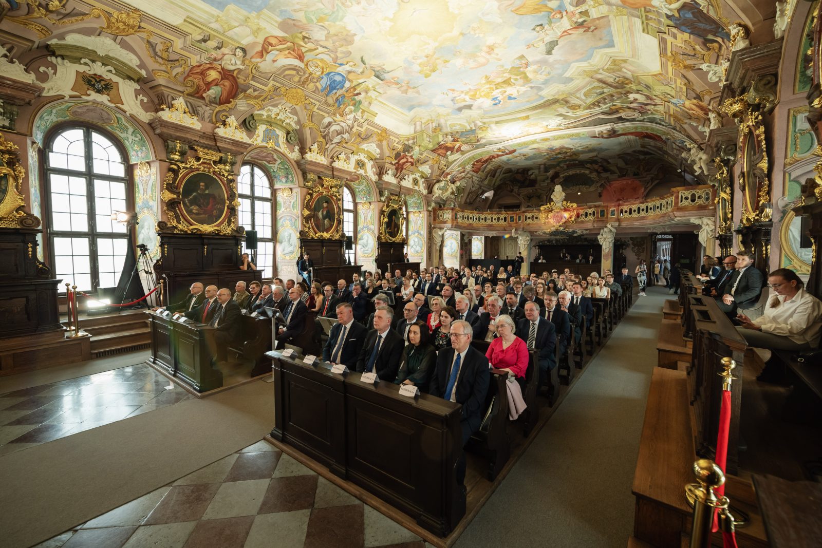 sala z malowidłami na suficie i wieloma osobami siedzącymi w ławach