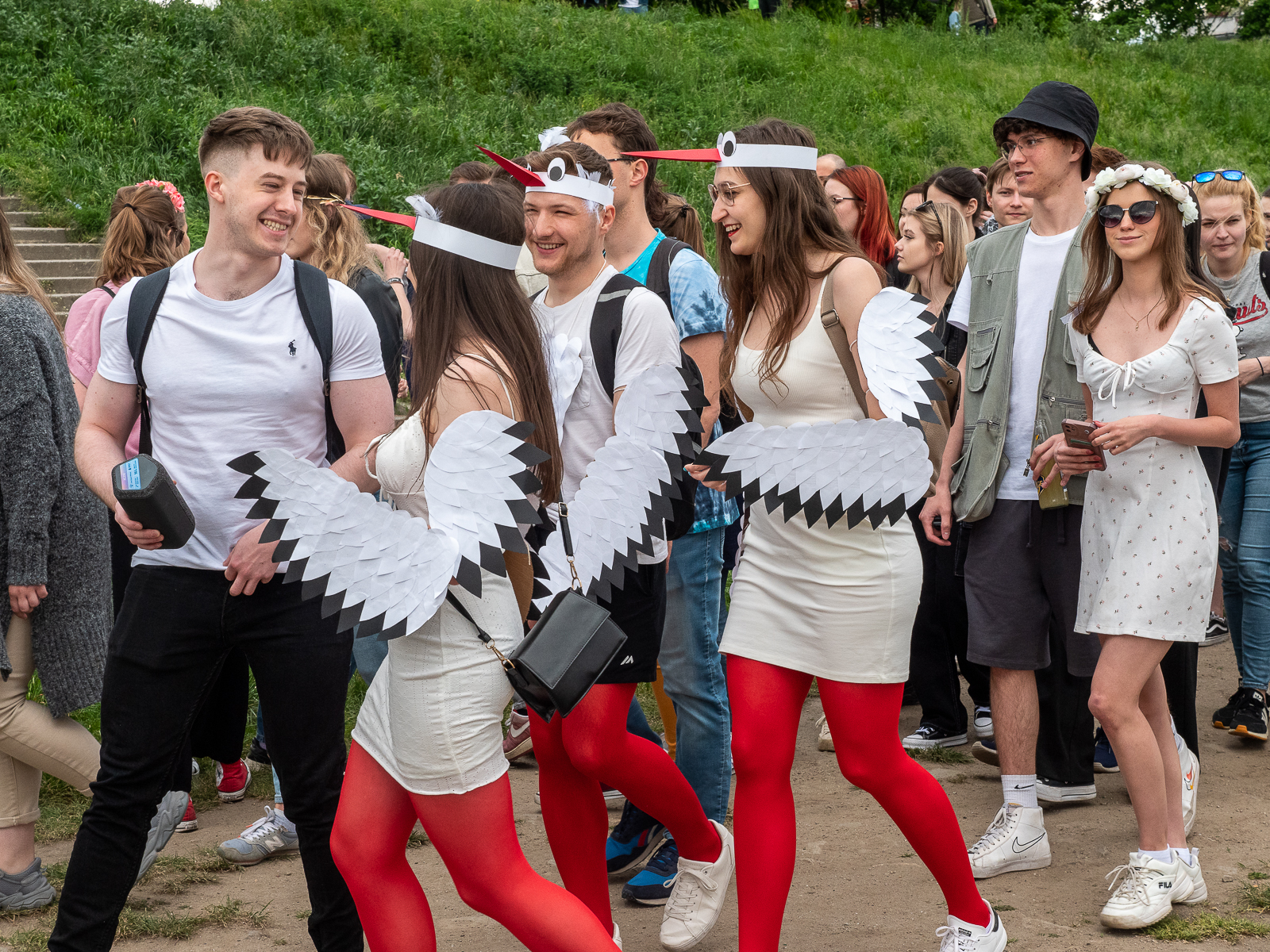 Ludzie idący w pochodzie juwenaliowym ulicami Wrocławia. Na pierwszym planie troje studentów w strojach bocianów.