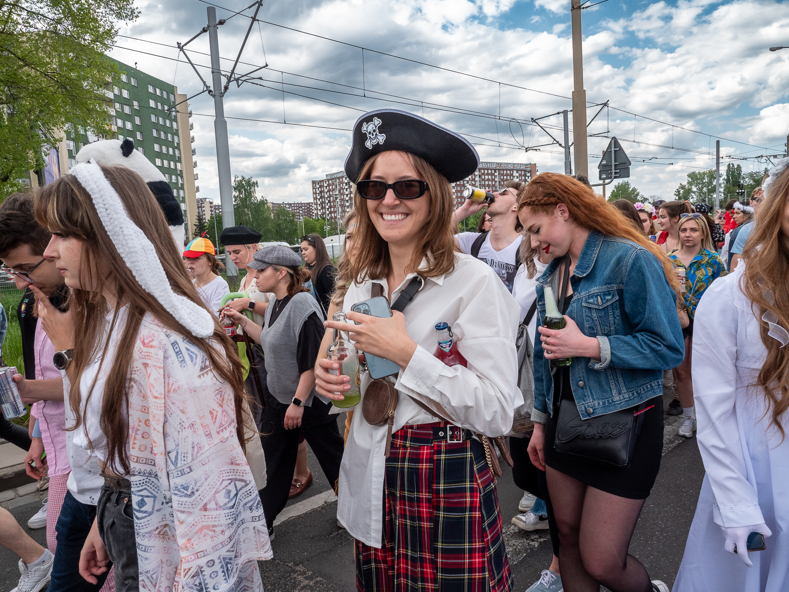 Ludzie idący w pochodzie juwenaliowym ulicami Wrocławia. Na pierwszym planie studentka przebrana za piratkę.