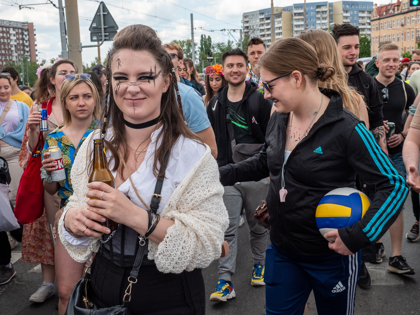 Ludzie idący w pochodzie juwenaliowym ulicami Wrocławia. Na pierwszym planie dziewczyna w białej bluzce.