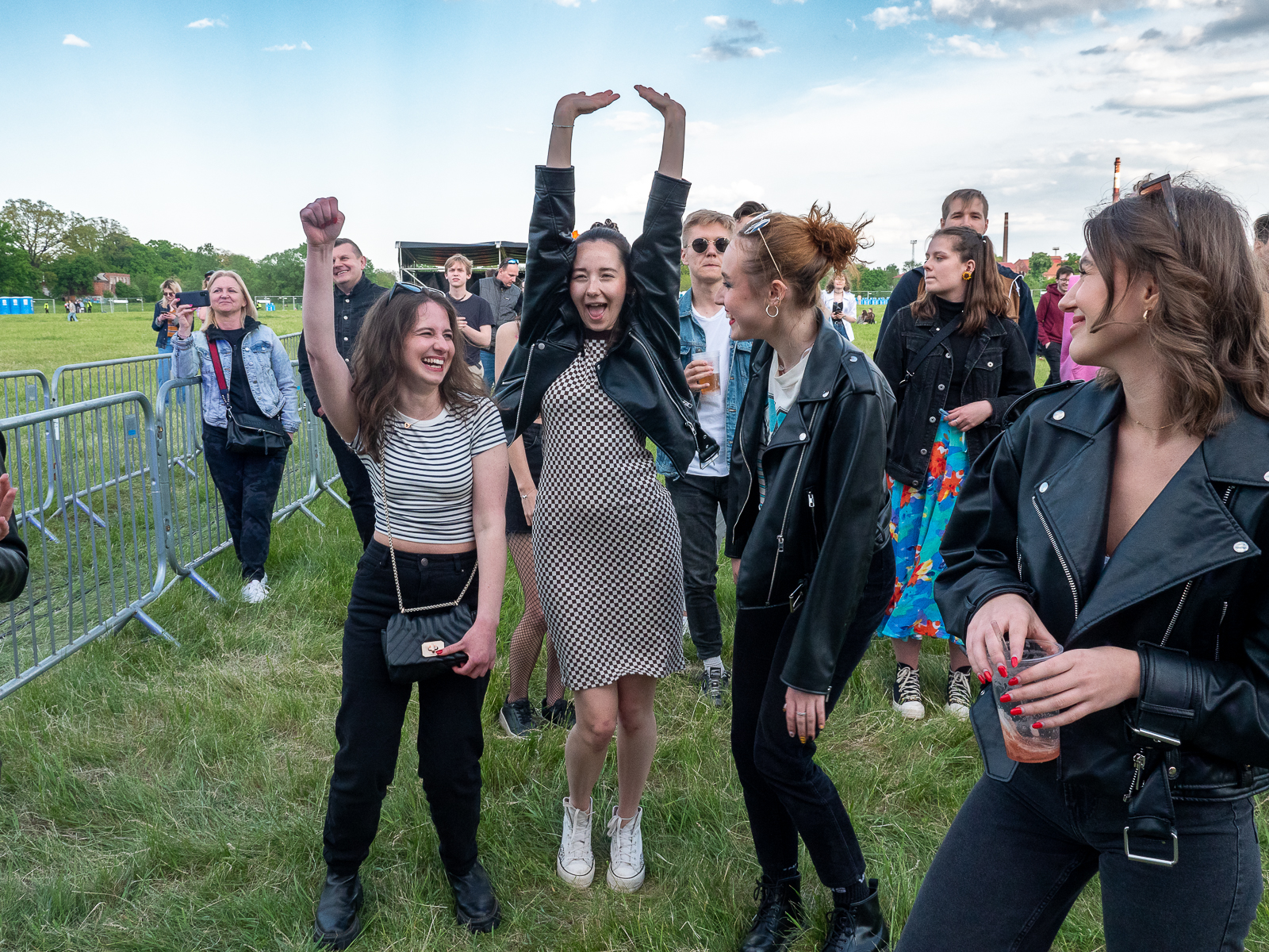 Grupa bawiących się na koncercie studentów i studentek. Studentka na środku ma ręce podniesione do góry.