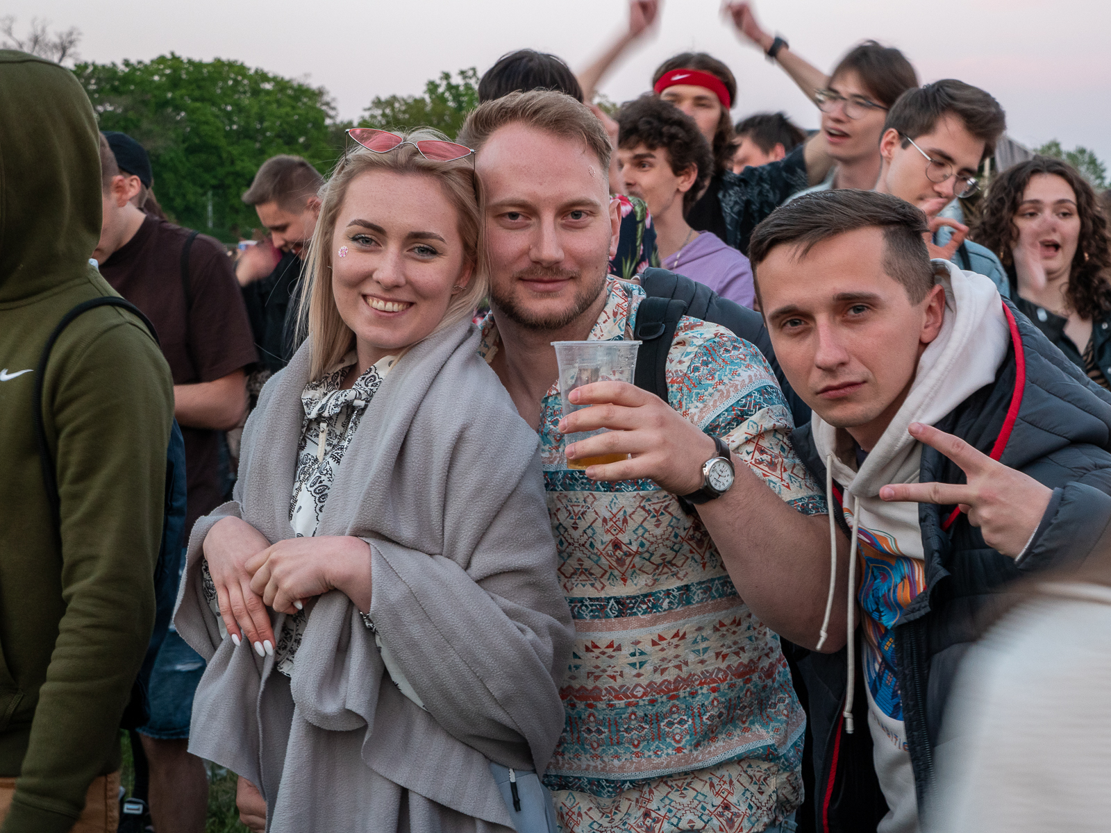 Dwóch studentów i studentka bawiący się na koncercie.