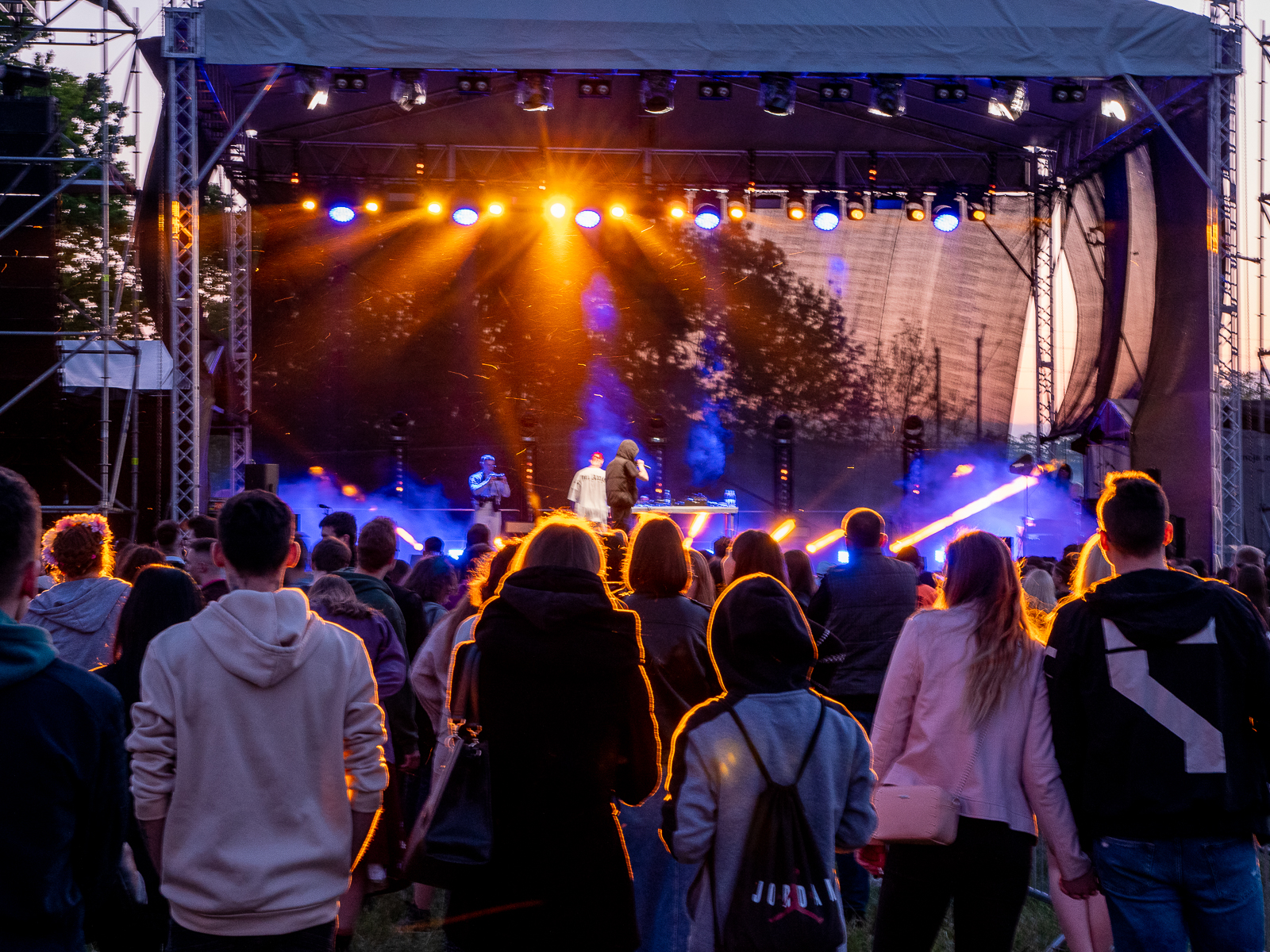Scena, na której trwa koncert. Przed sceną publicznosć. Na scenie kolorowe światła.