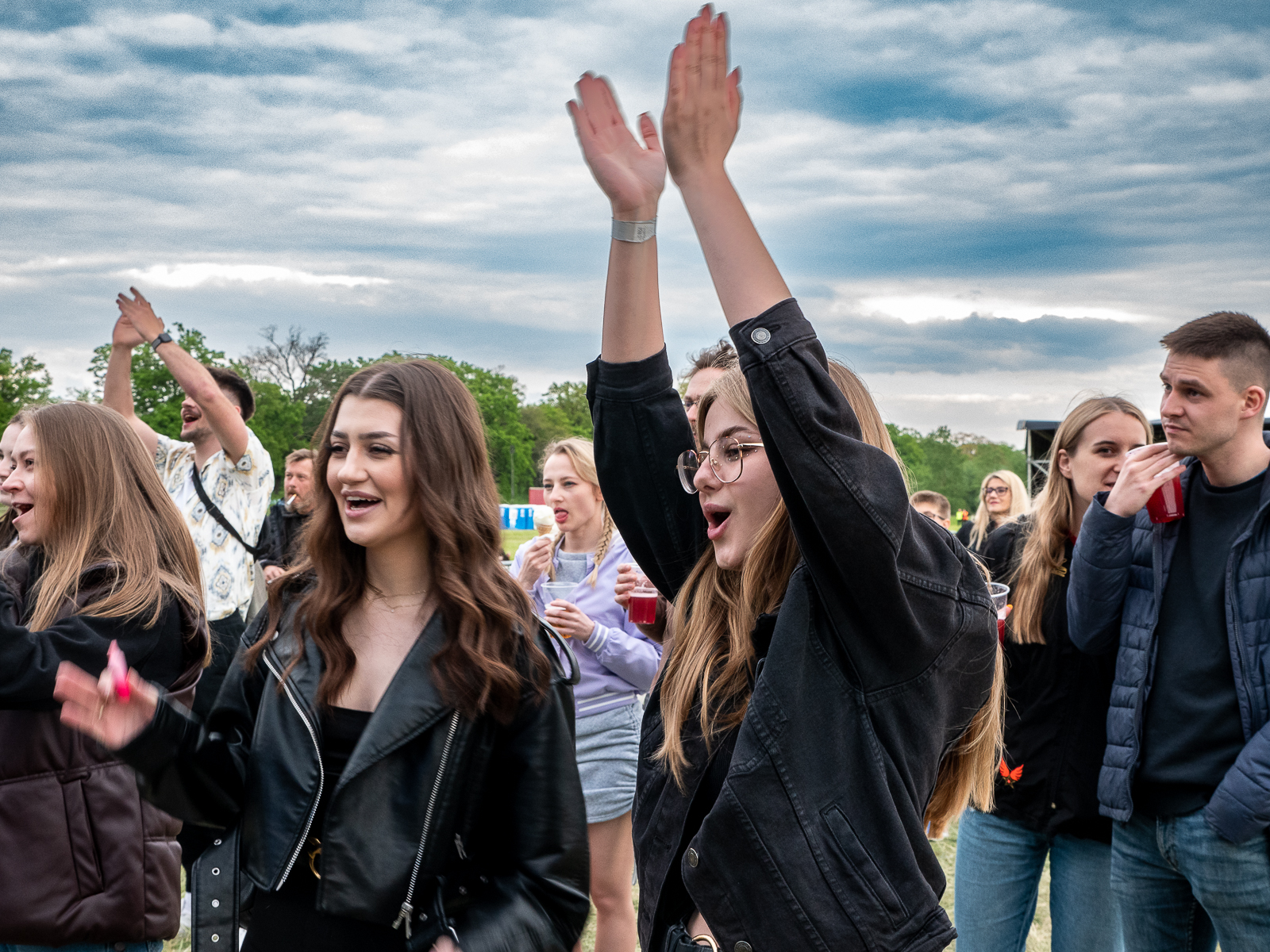 Grupa studentów i studentek bawiąca się na koncercie podczas Juwenaliów. Studentka na pierwszym planie klaszcze w ręce nad swoją głową.