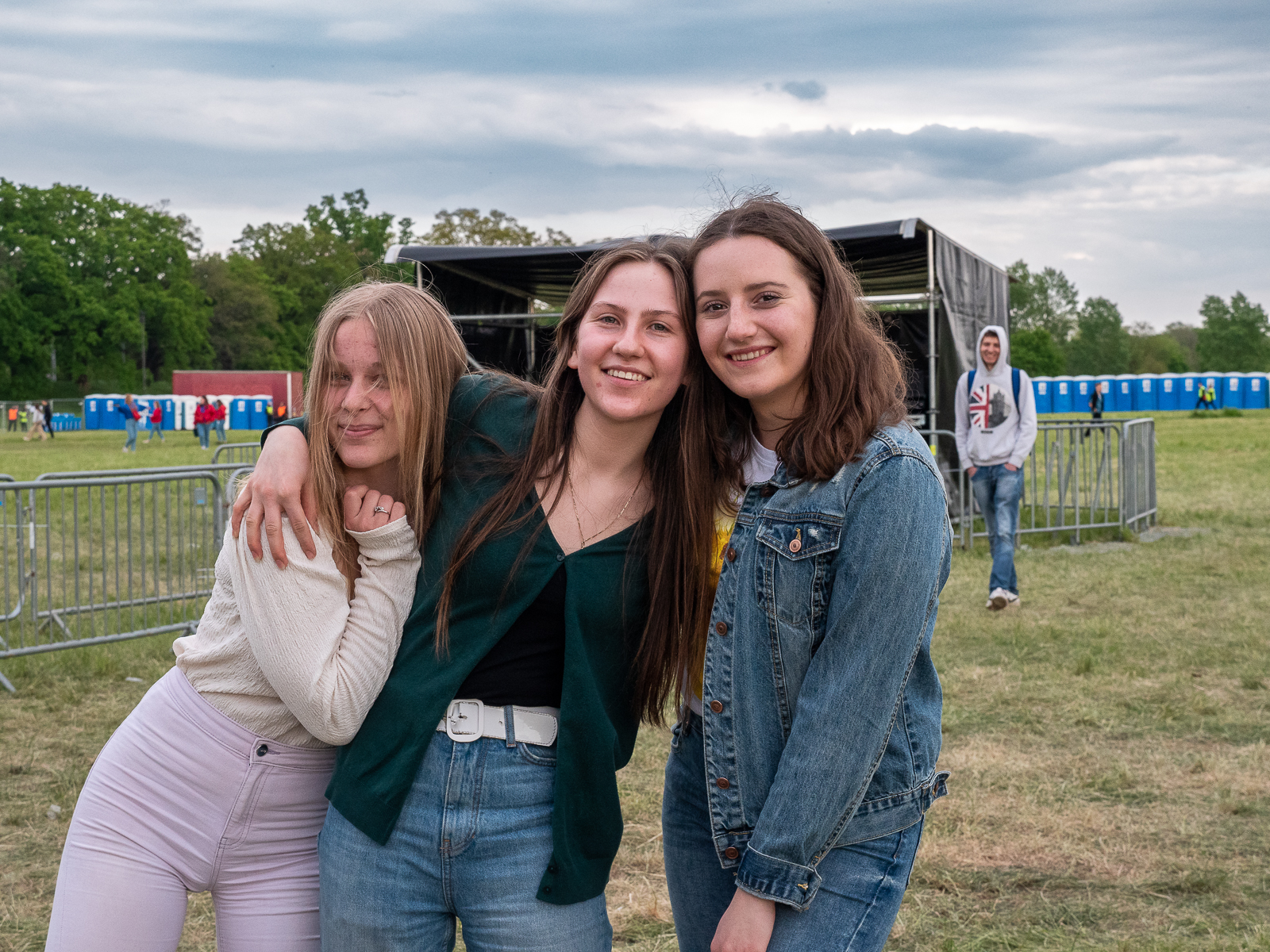 Trzy uśmiechnięte studentki bawiące się na koncertach podczas Juwenaliów. Stoją w rzędzie, trzymając się za ramiona.