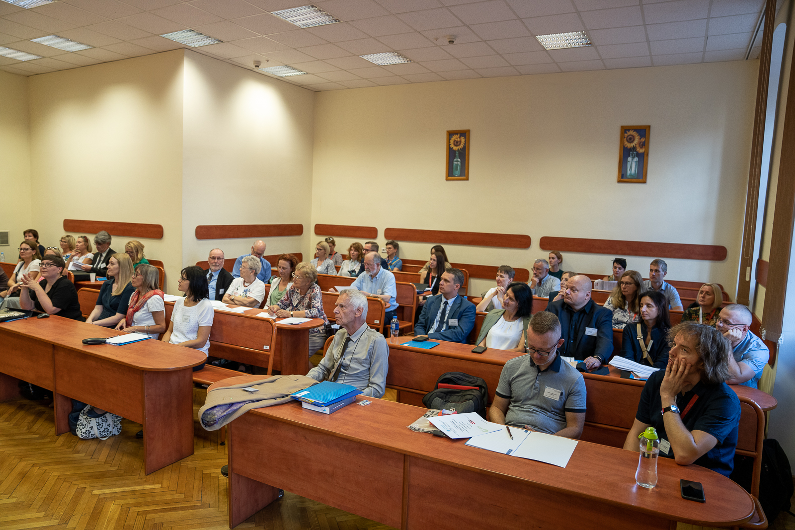 grupa ludzi siedząca w ławkach na sali konferencyjnej