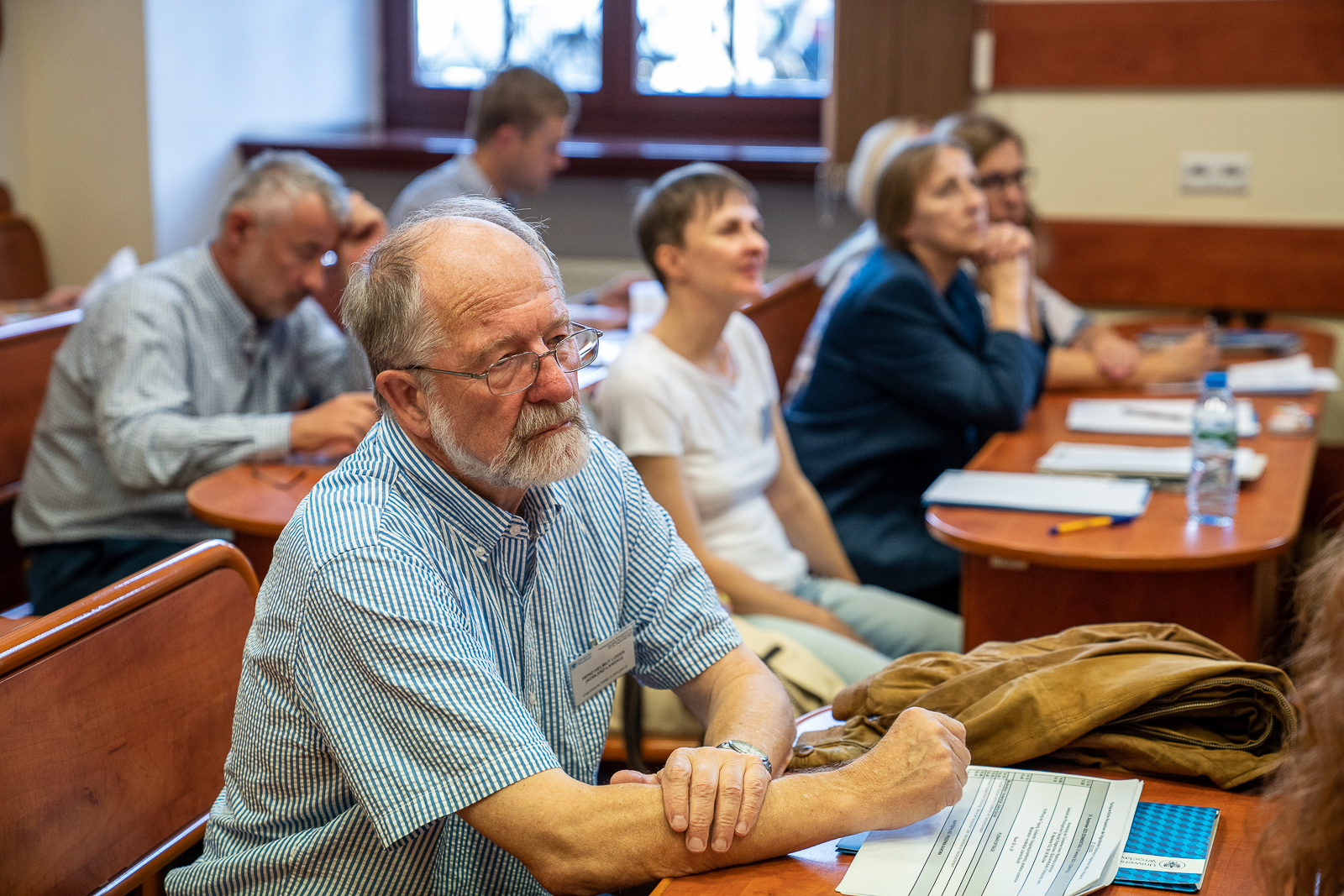 grupa ludzi siedząca w ławkach na sali konferencyjnej