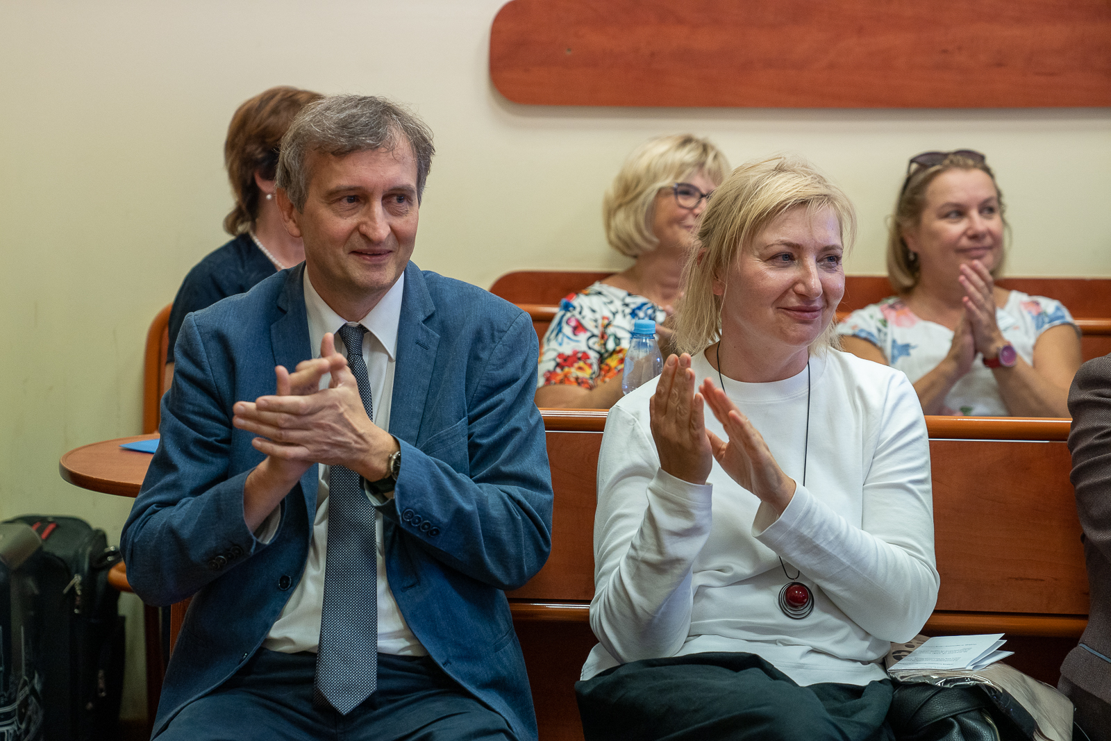 grupa ludzi siedząca w ławkach na sali konferencyjnej