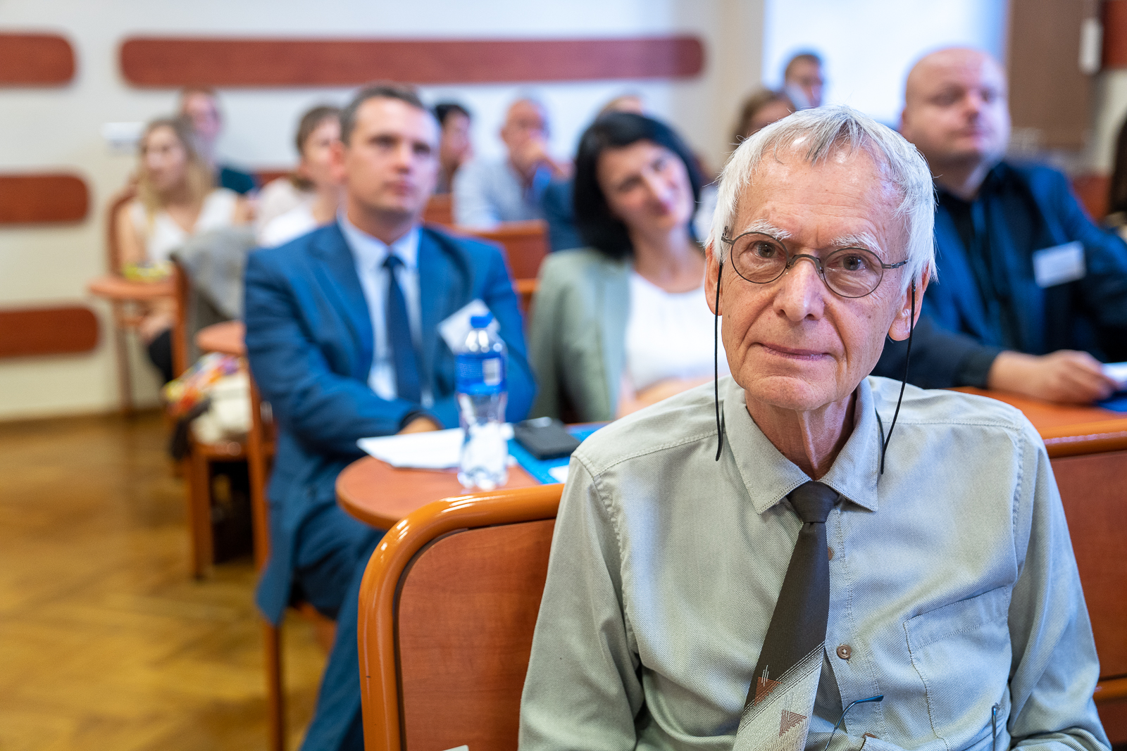 grupa ludzi siedząca w ławkach na sali konferencyjnej