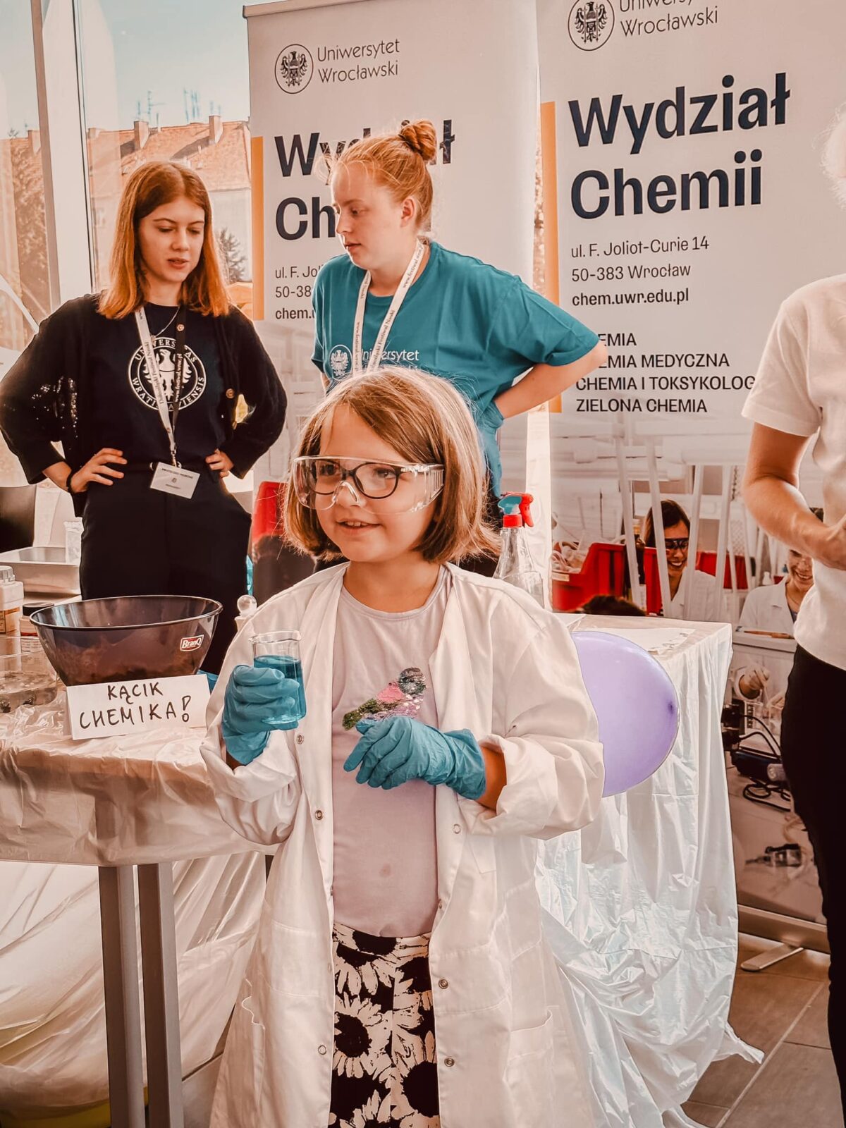 Dziewczynka w fartuchu laboratoryjnym i okularach.