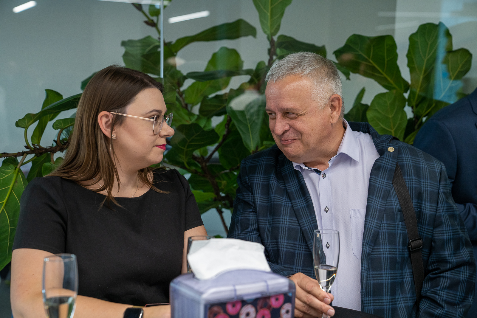 Mężczyzna i kobieta rozmawiająct ze sobą. Kobieta w czarnej bluzce, mężczyzna w jasnej koszuli i marynarce w kratkę