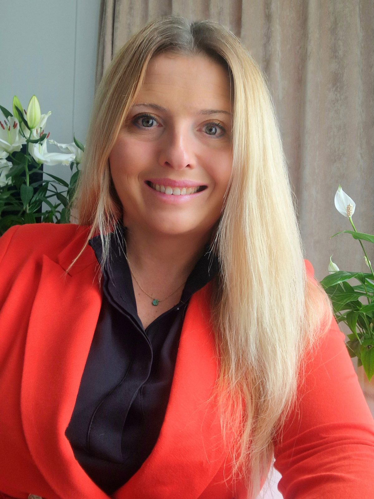 młoda kobieta o długich blond włosach w czerwonej marynarce i czarnej koszuli