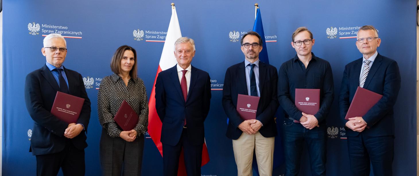 Grupa pięciu osób, z których cztery trzymają czerwone teczki