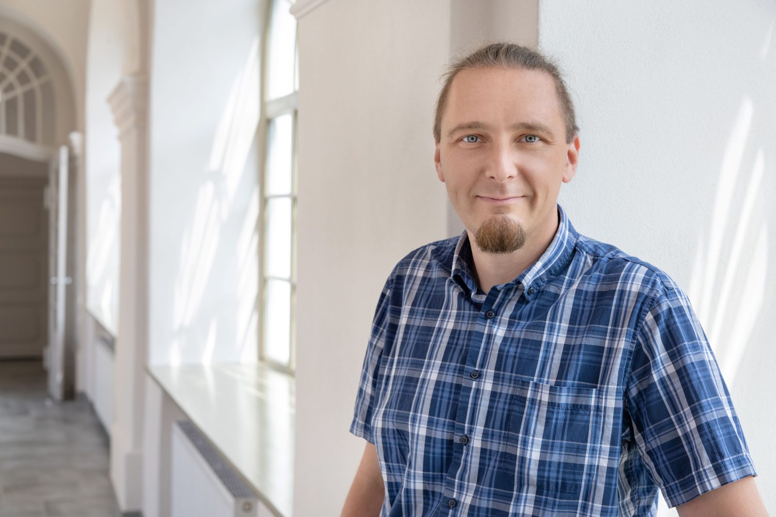 młody mężczyzna z brodą w niebieskiej koszuli w kratę