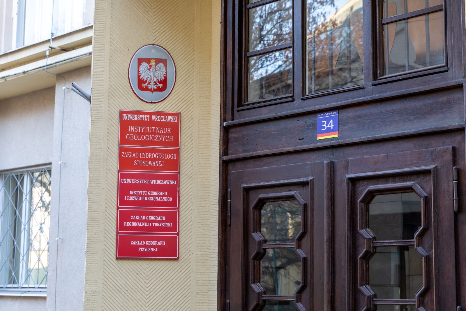 fragment bydynku z drewnianymi drzewiami, na którym umieszczono czerwone tablice