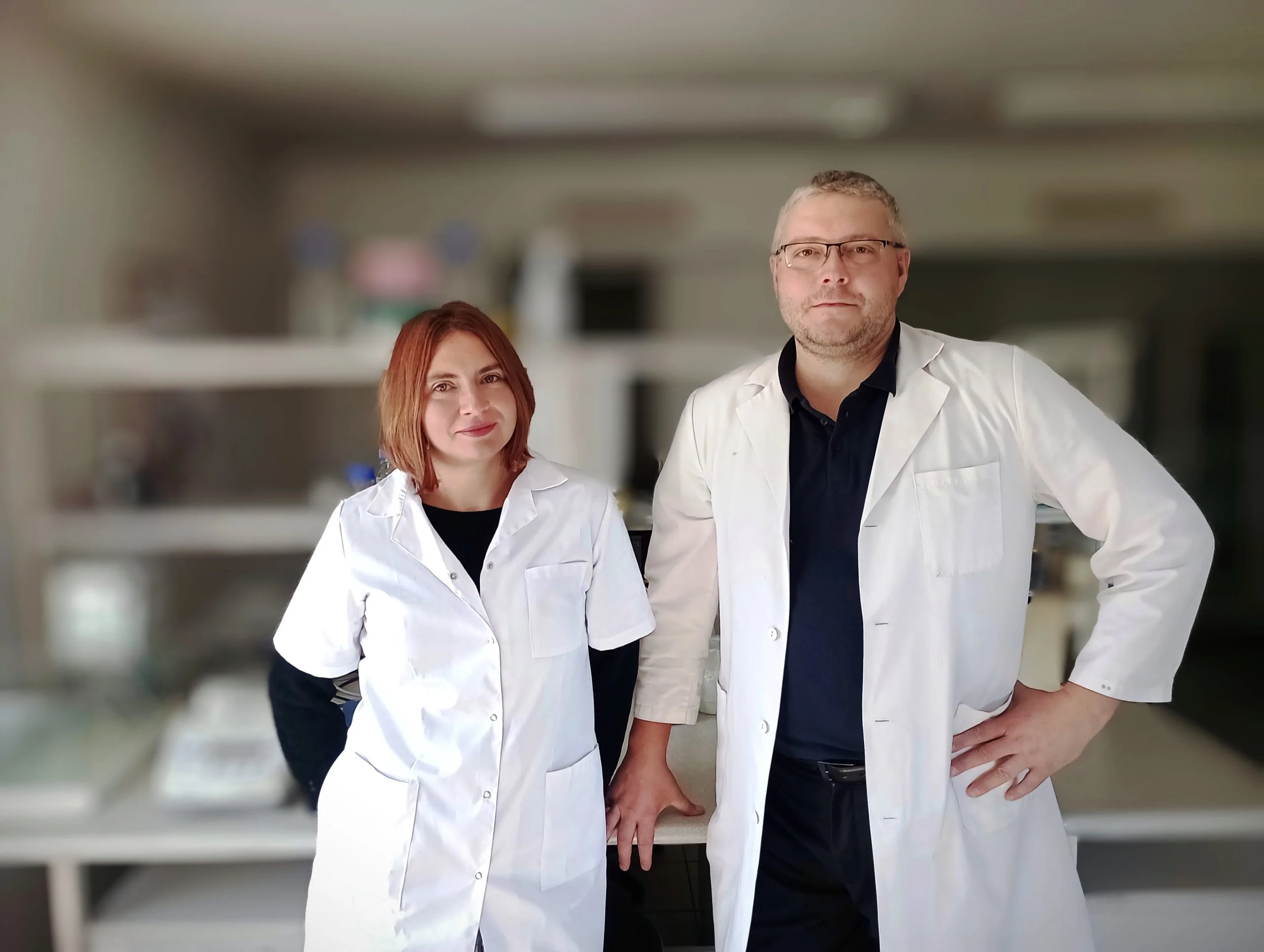 młoda kobieta o rudych włosach srednej długości i młody mężczyzna o siwych włosach, oboje ubani w białe fartuchy