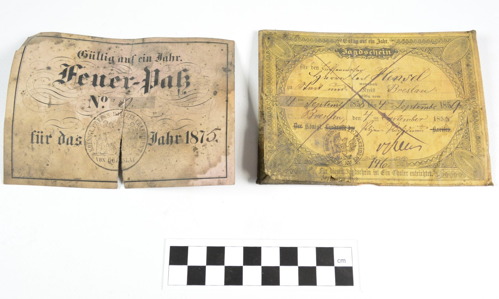 Pamiątki po policji odnalezione pod podłogą strychu. Pozwolenie na broń z 1875 r. oraz pozwolenie na polowanie w granicach Wrocławia i powiatu wrocławskiego wydane na rusznikarza Carla Hensela 4 września 1858 r. Oba dokumenty opatrzone pieczątkami prezydium policji. Fot. P. Duma.