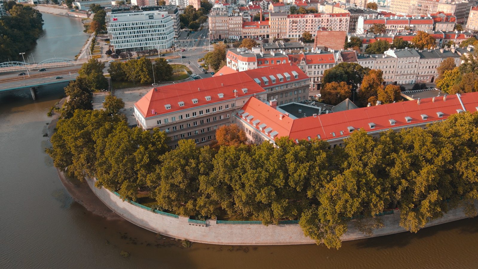 zdjęcie przedstawiające z drona wydział fizyki i astronomii, widać rzekę odrę, zieleń, budynki