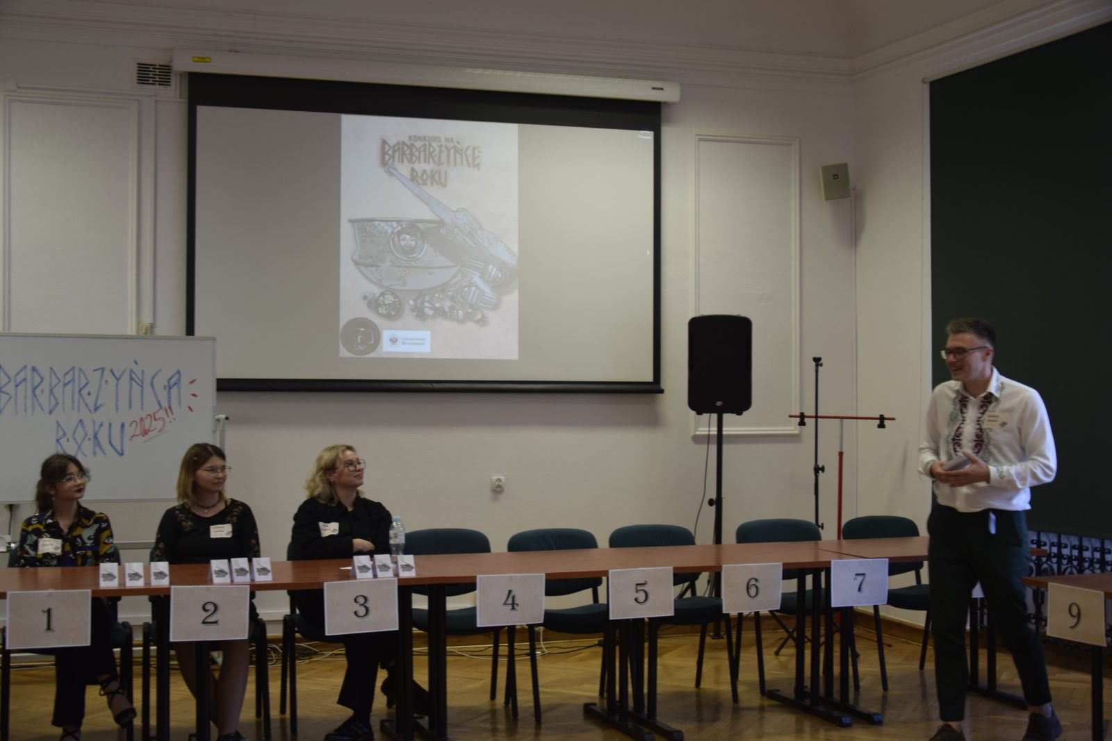 meżczyzna mówiący coś do trzech siedzących kobiet