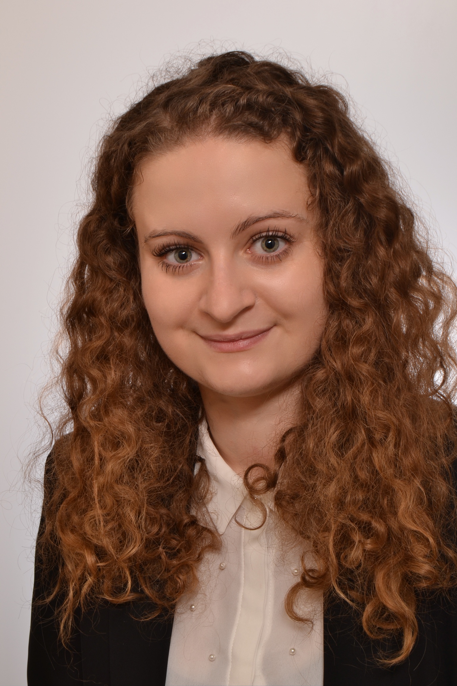 zdjęcie przedstawiające młodą, uśmiechniętą kobietę, ubraną wizytowo