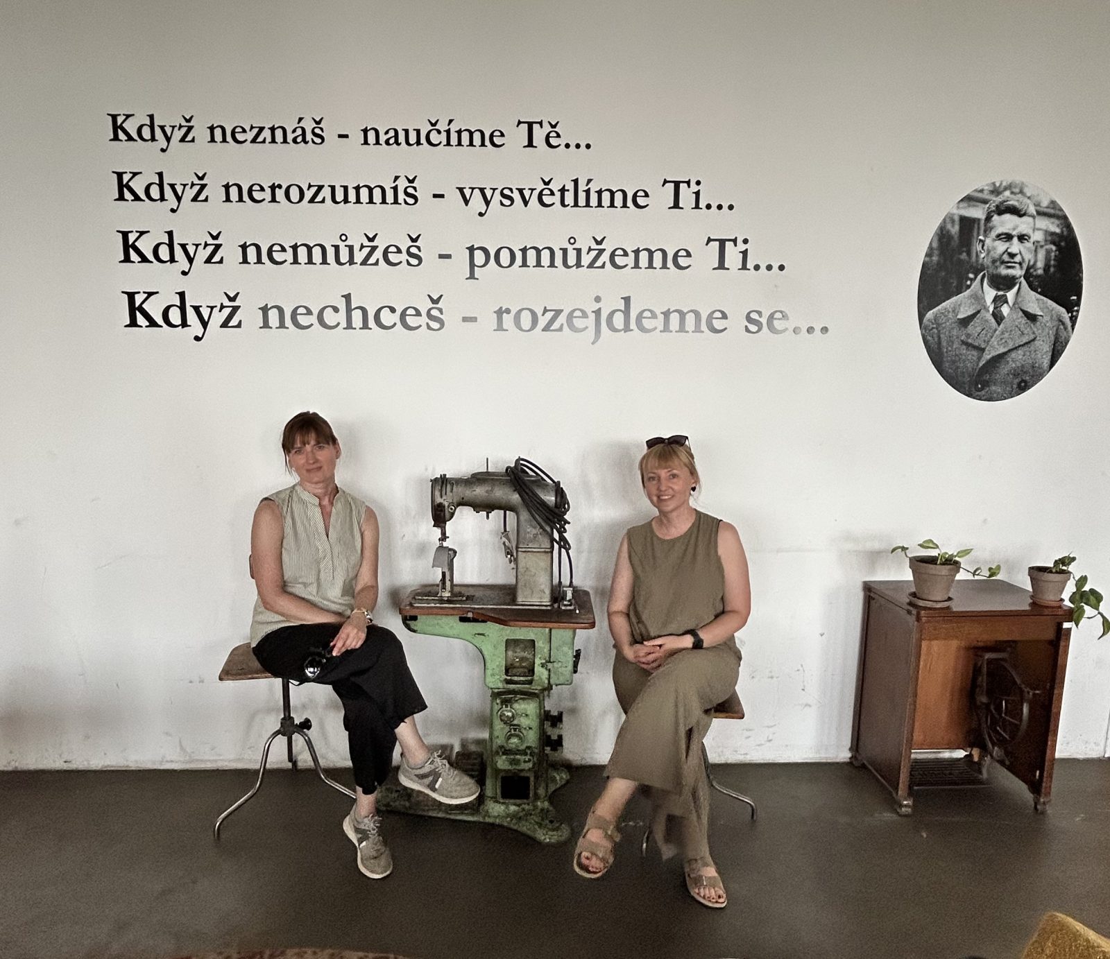 dwie kobiety siedzą, pomiędzy nimi maszyna do szycia