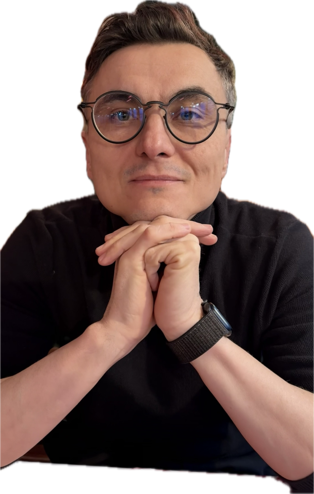 młody mężczyzna ubrany wizytowo, ma okulary i uśmiecha się