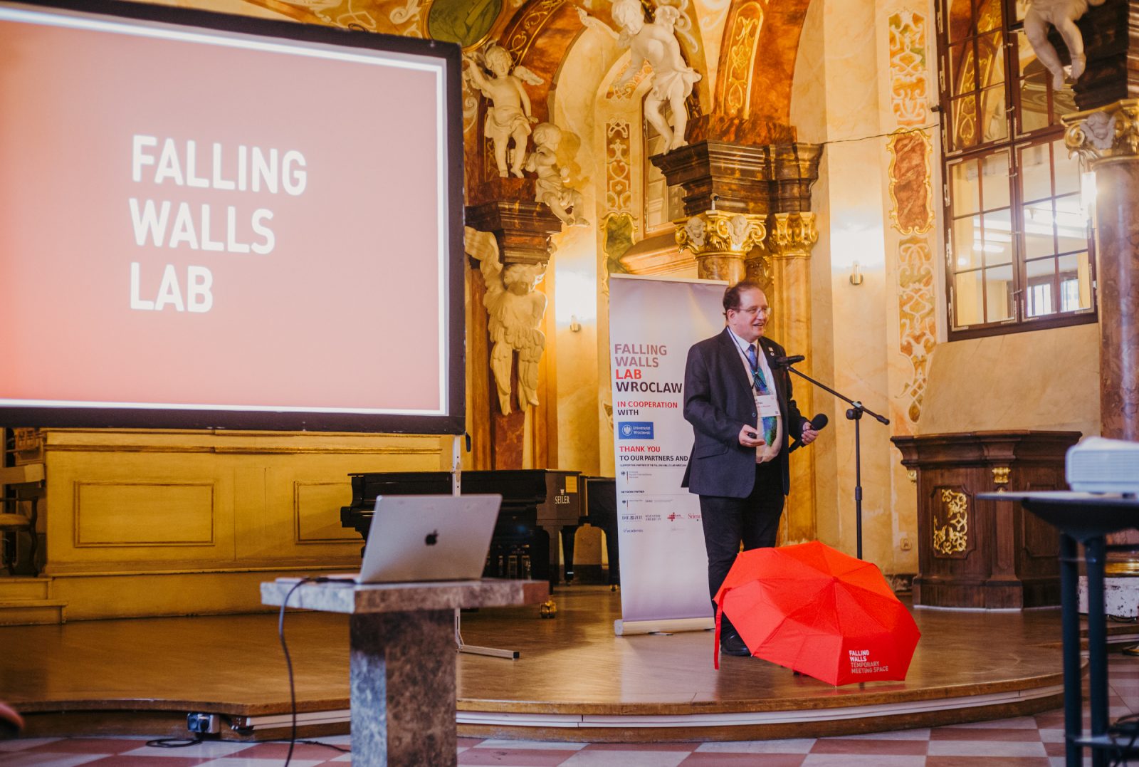 zdjęcie wykonane w barokowej sali, przedstawiające naukowca ubranego wizytowo, rozpoczynającego wydarzenie falling walls podczas poprzedniej edycji