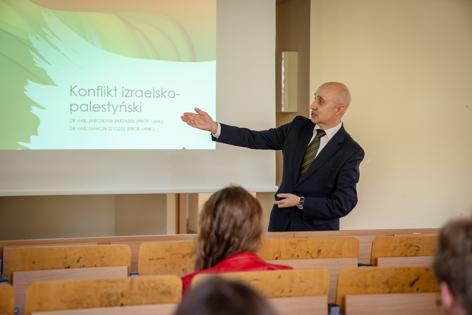 mężczyzna wskazujący reką na slajd z napisem: konflikt izraelsko-palestyński