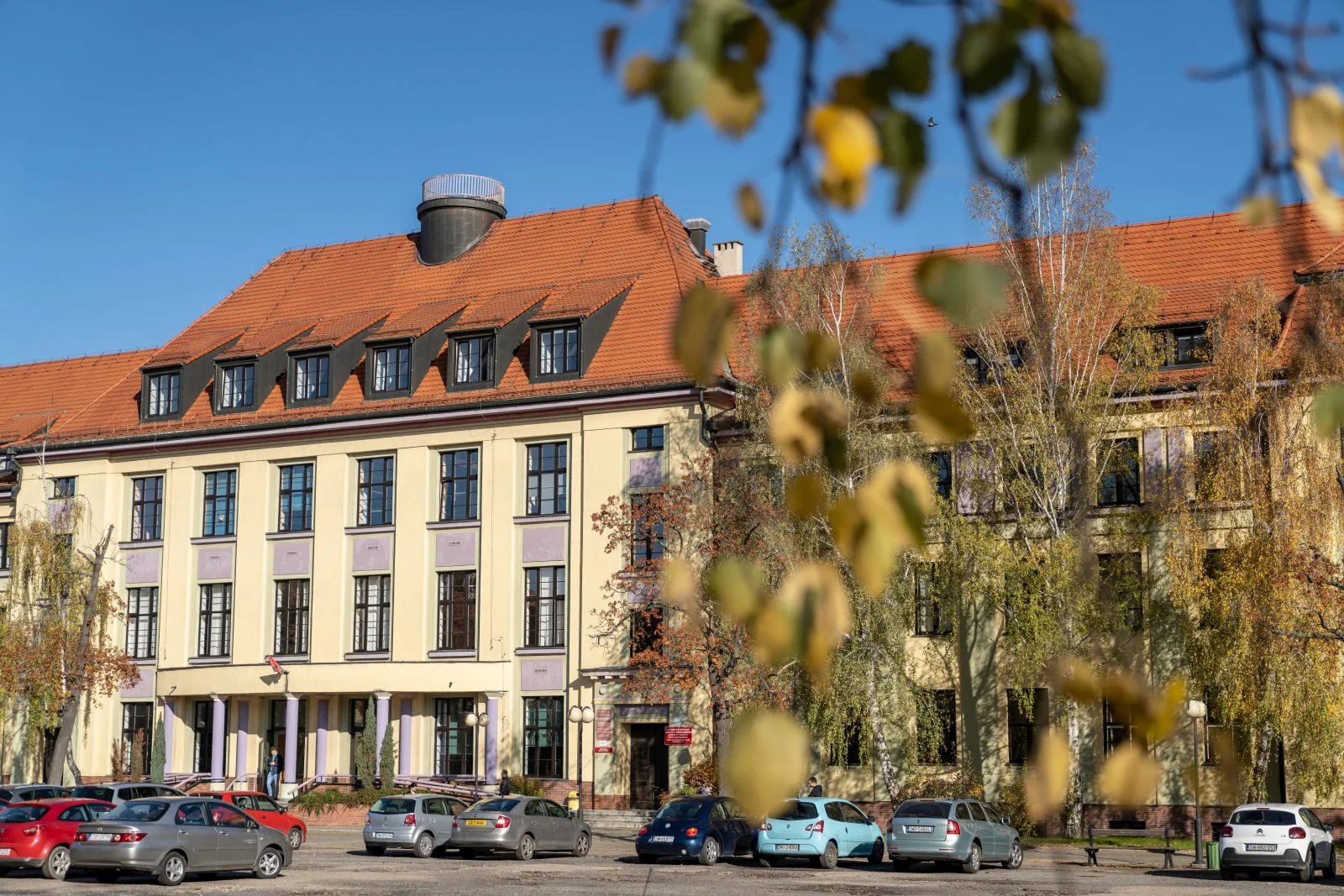 duży żółty bydynek, przed nim samochody