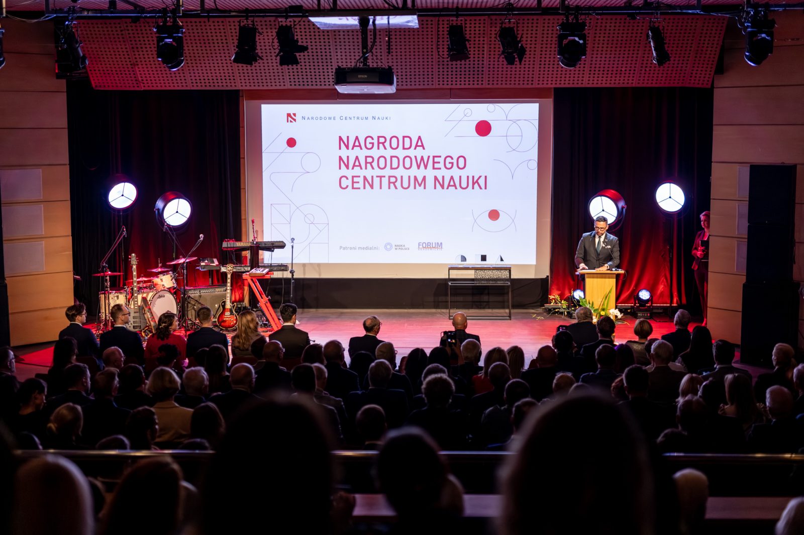 ludzie w sali konferencyjnej z ekranem z napisem Nagroda narodowego centrum nauki
