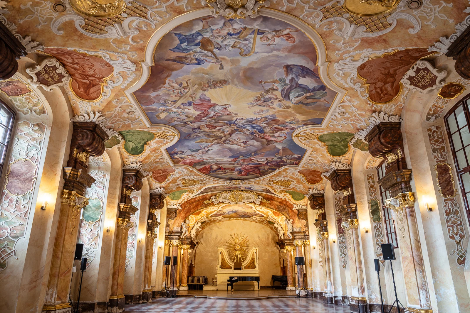 Wnętrze barokowej sali z freskiem na suficie, kolumnami po bokach i organami