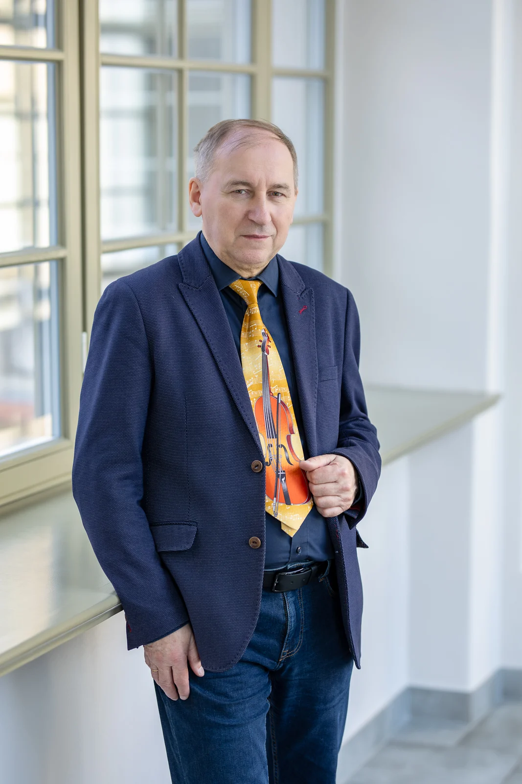 zdjęcie przedstawiające mężczyznę ubranego wizytowo, stoi w korytarzu