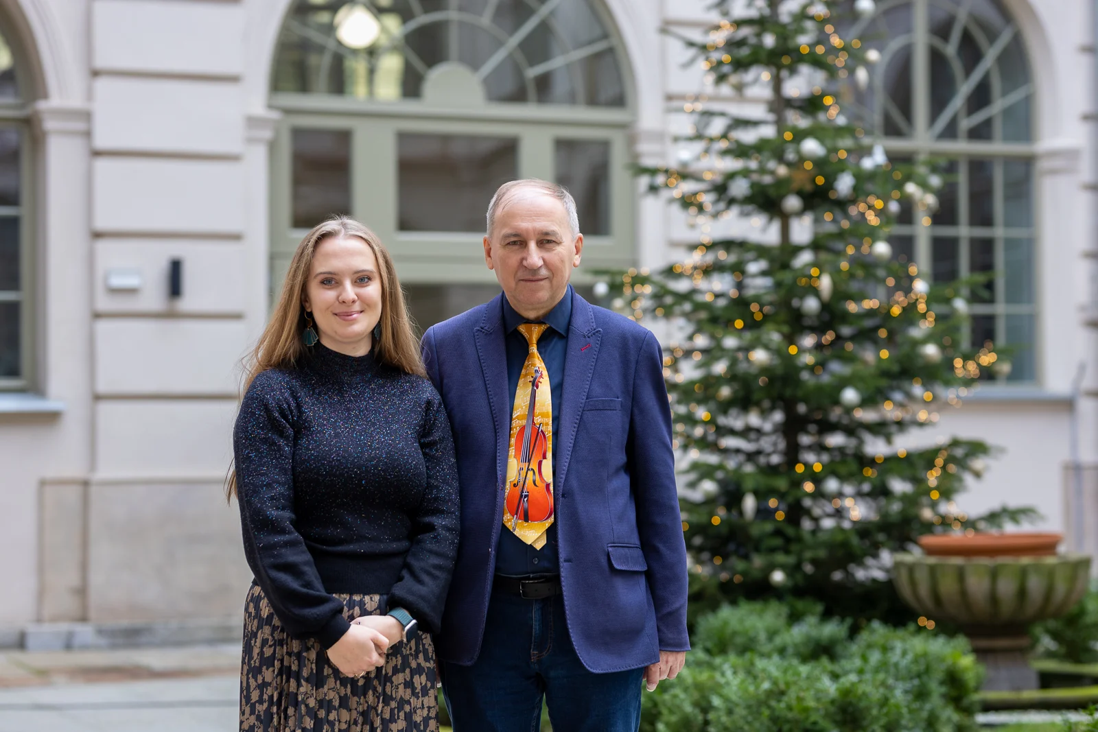 zdjęcie przedstawiające parę, kobietę i mężczyznę na patio w budynku, z tyłu stoi choinka