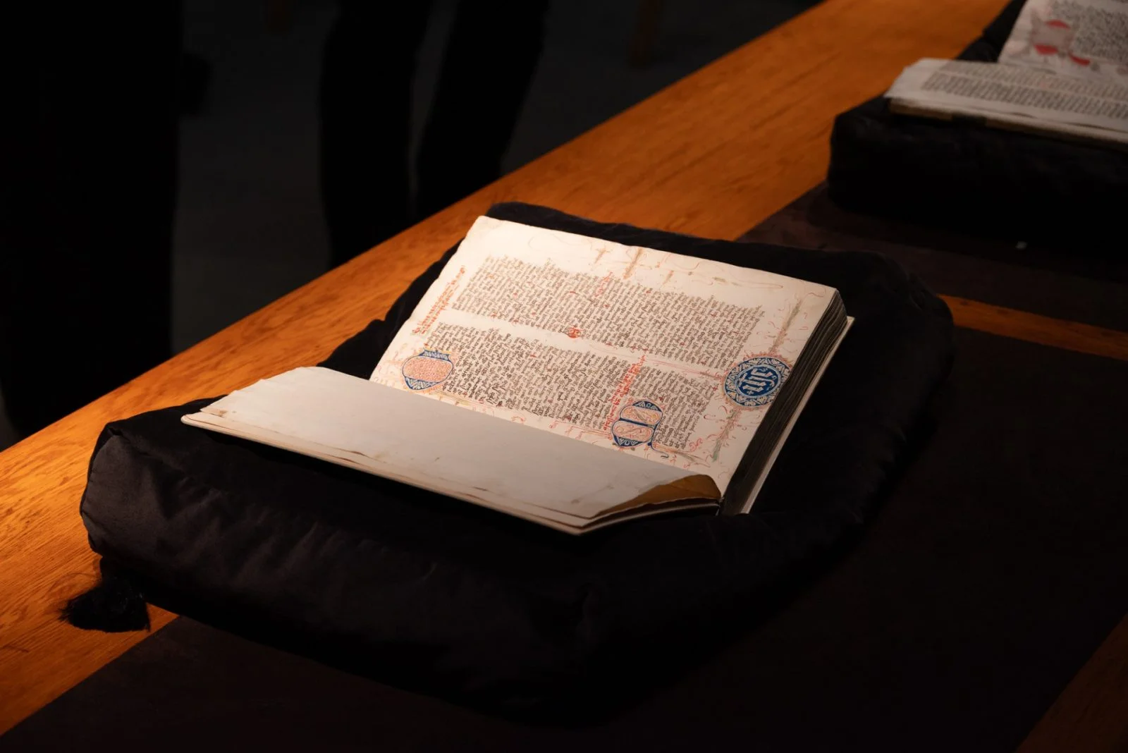 średniowieczna, bogato zdobiona książka, leżąca na stole, oświetlona z góry światłem lampy