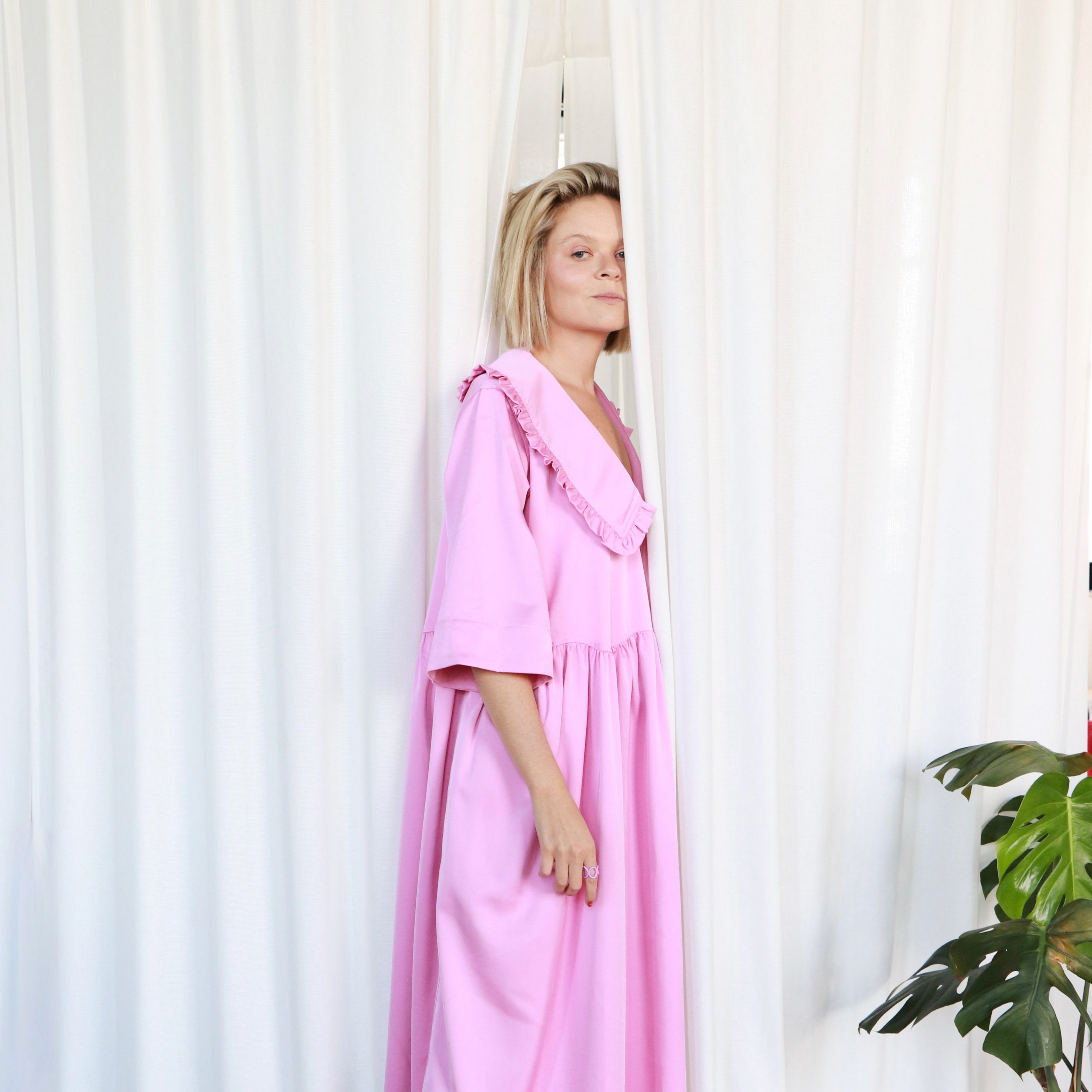 kobieta w długiej sukni częściowo schowana za zasłoną