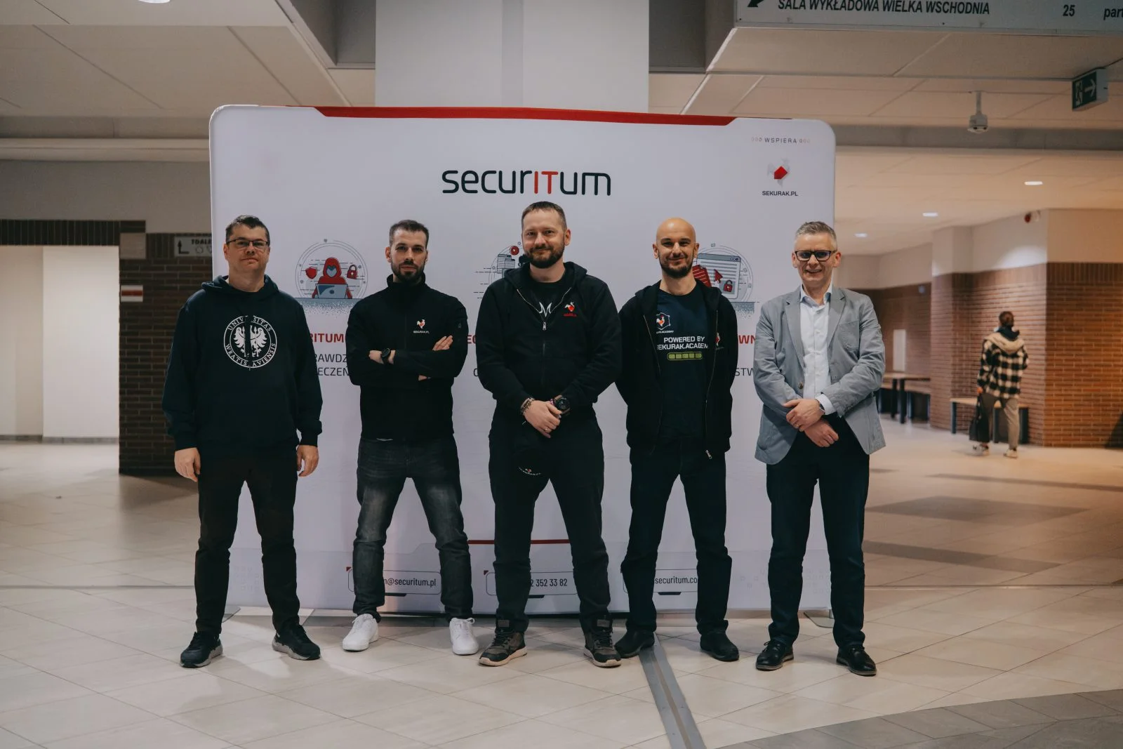 pięć osób stojących na tle ścianki z napisem SECURITUM