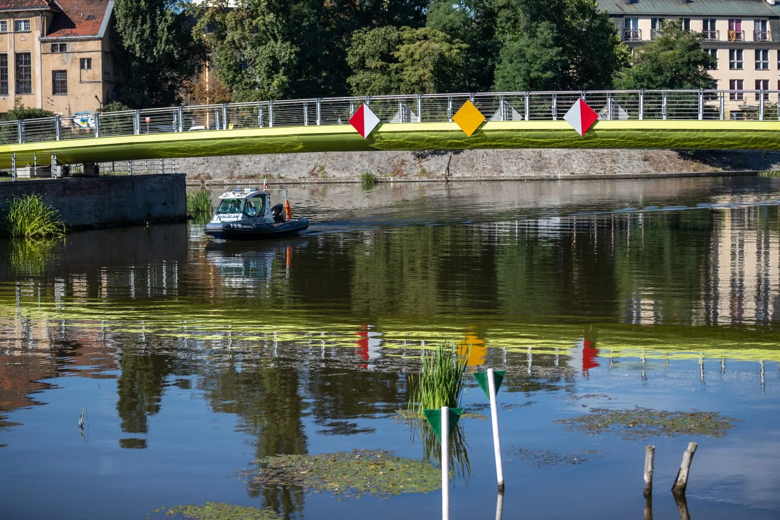 rzeka Odra z widokiem na most na wyspę słodową. pod mostem przepływa policyjna motorówka