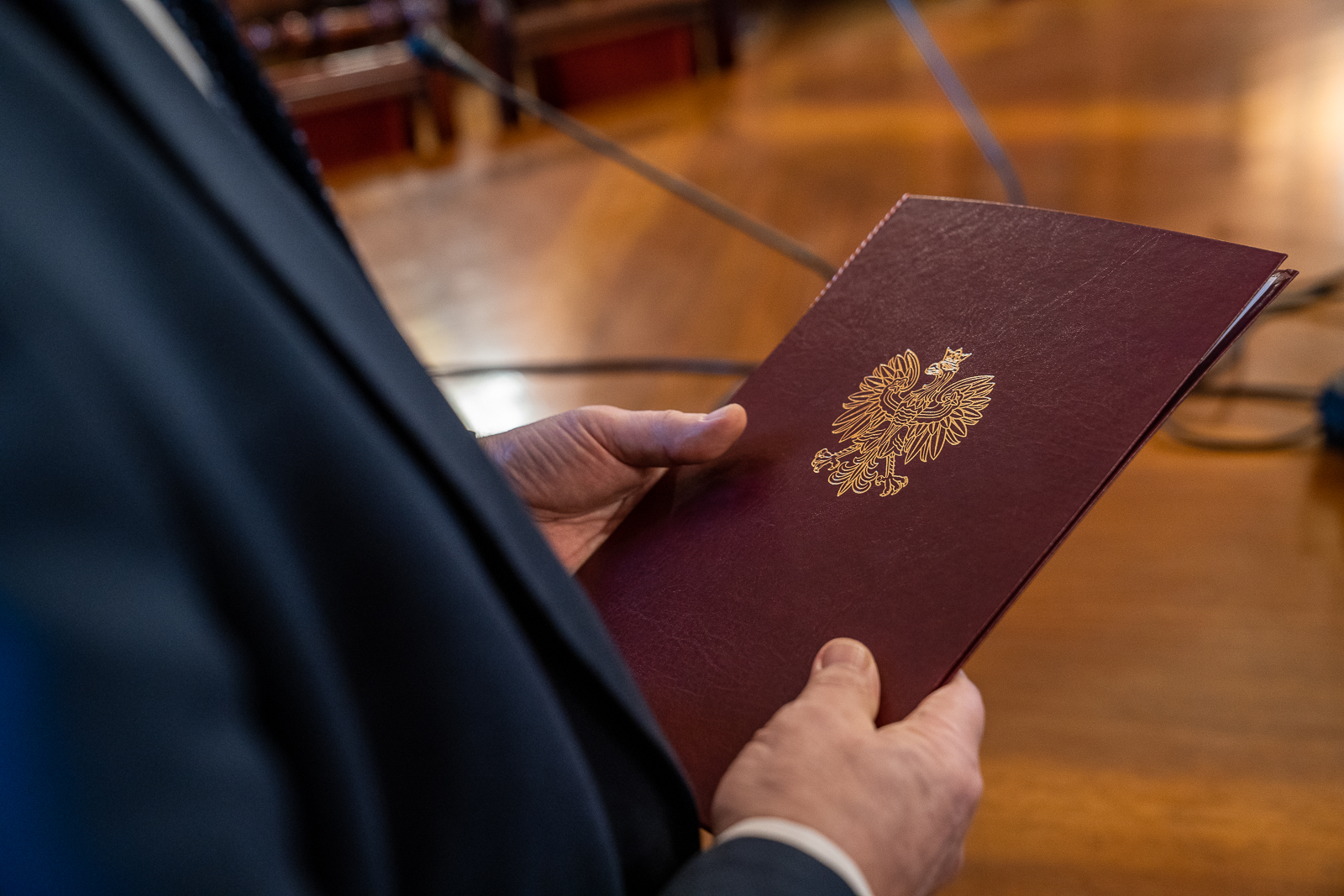 ręce trzymające okładkę dyplomu z polskim godłem