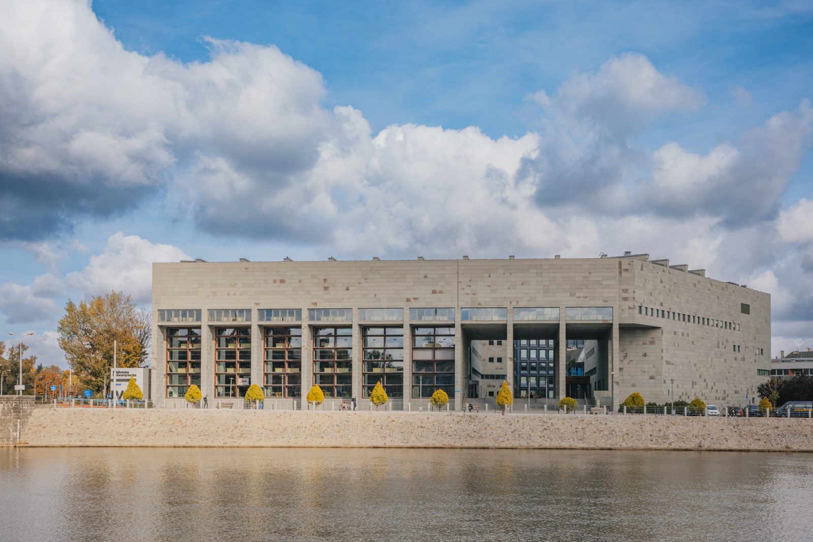 duży szary budynek nad rzeką