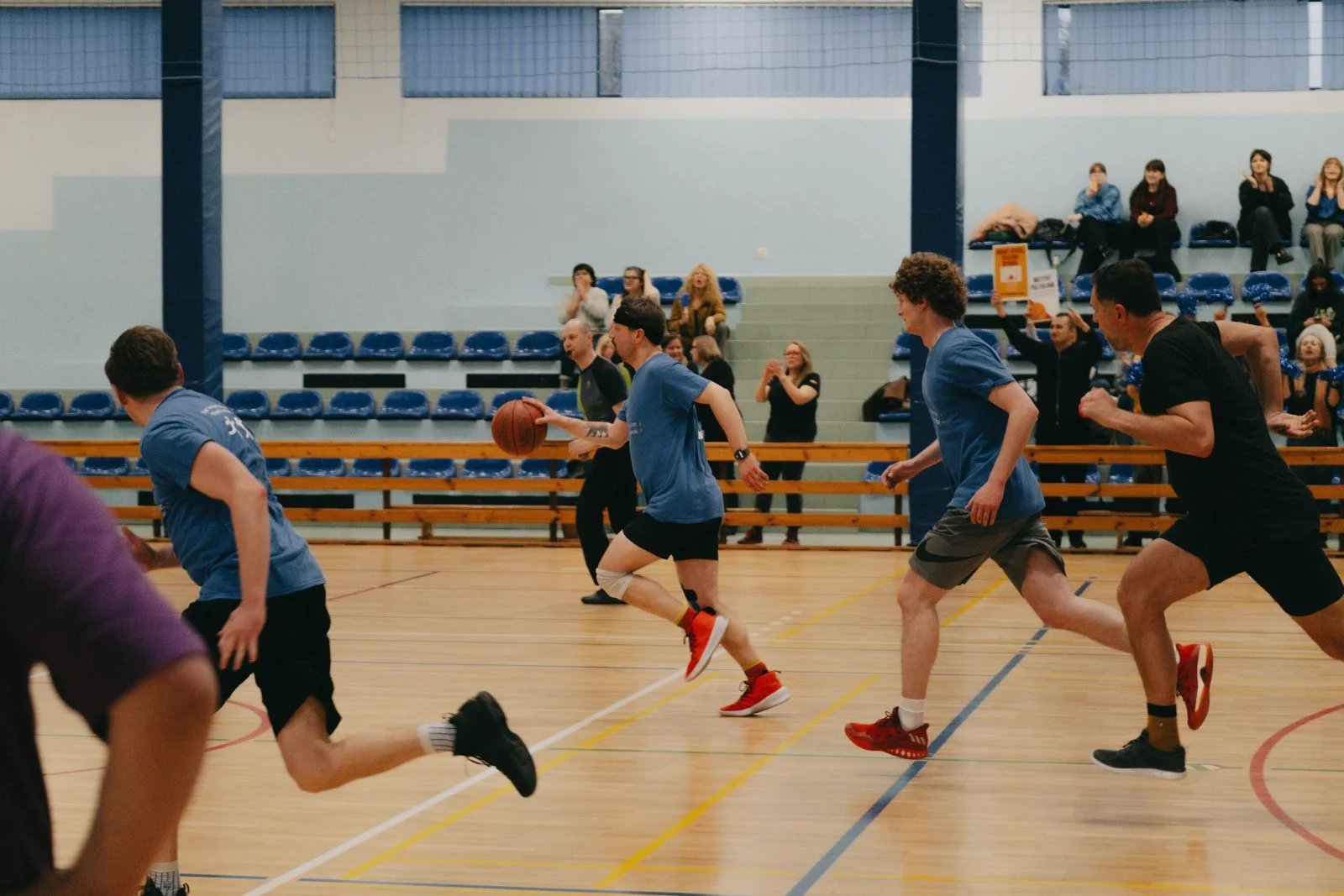 grupa osób na boisku sportowym do koszykówki rozgrywa mecz