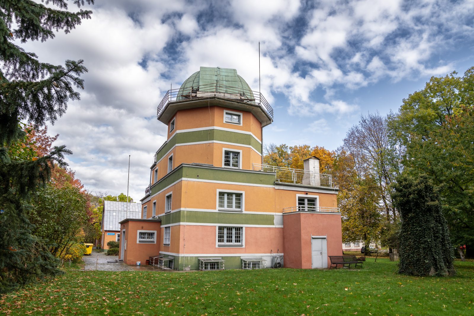 duży budynek z wieżą zakończoną kopułą, stojący na polanie wśród drzew, z dużymi oknami i tarasem widokowym